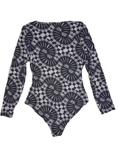 A long-sleeve bodysuit featuring an all-over black and white geometric pattern with circular sunburst and checkerboard motifs, laid flat against a white background.